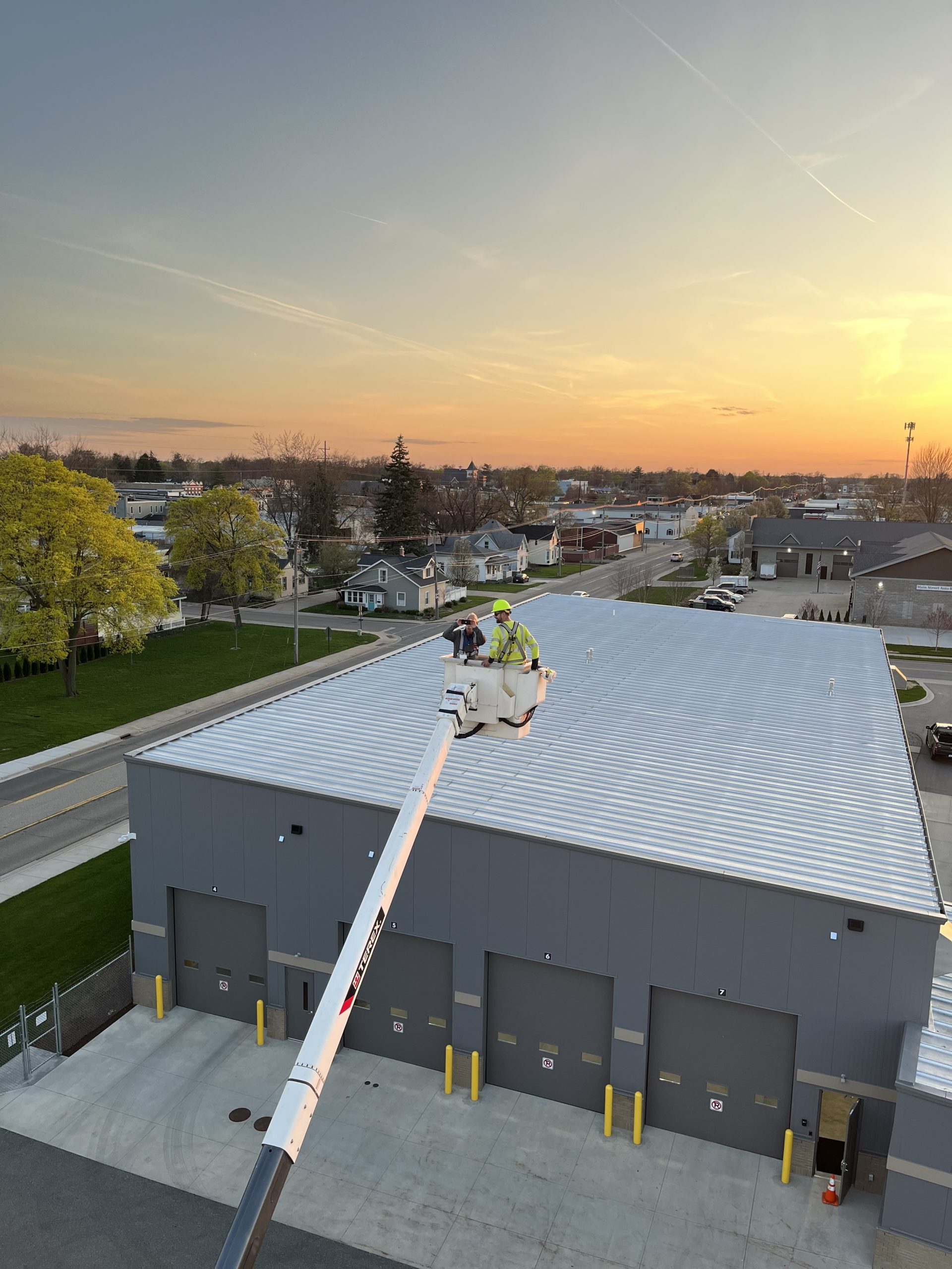Two people in an electric bucket truck at sunset